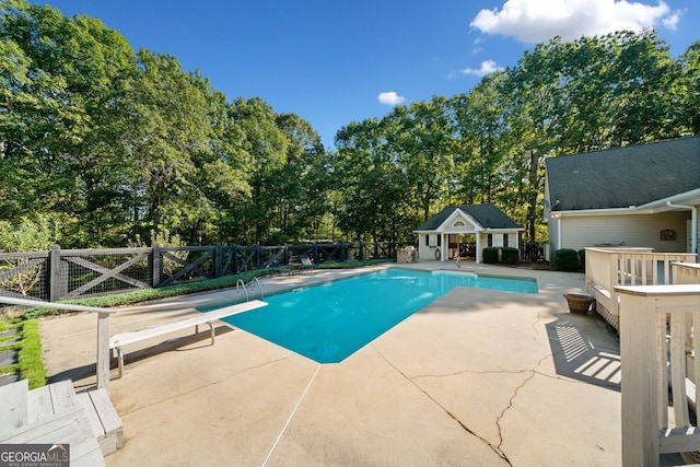 view of pool featuring an outdoor structure, a diving board, and a patio area