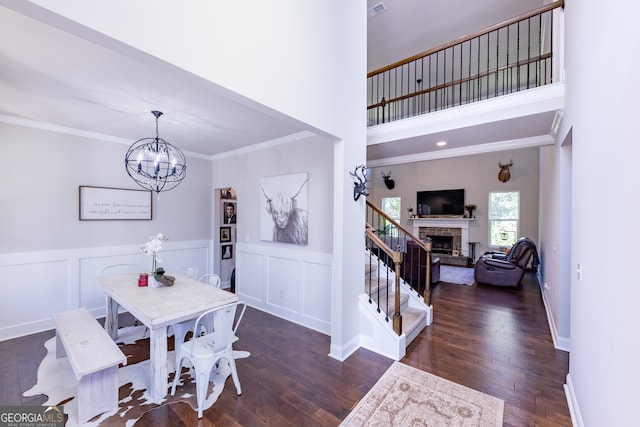 dining space featuring a notable chandelier, ornamental molding, dark hardwood / wood-style flooring, and a fireplace