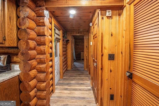 hall featuring light hardwood / wood-style floors, wood ceiling, and log walls