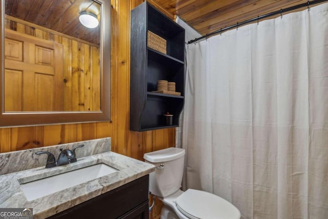 bathroom with toilet, wood ceiling, wood walls, and vanity