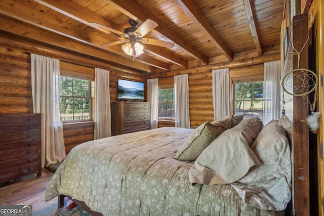 bedroom featuring beamed ceiling, hardwood / wood-style floors, and multiple windows