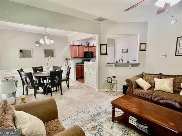 carpeted living room featuring ornamental molding and ceiling fan with notable chandelier