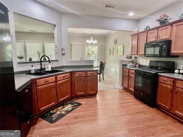 kitchen with a wealth of natural light, sink, black appliances, crown molding, and an inviting chandelier