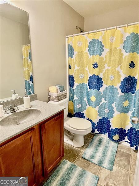 bathroom with vanity, toilet, a shower with shower curtain, and tile patterned flooring