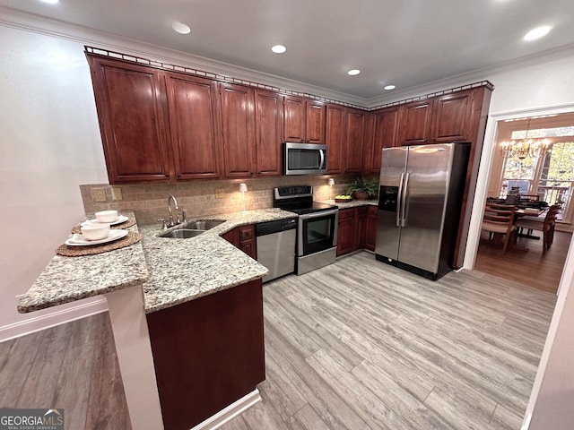 kitchen featuring backsplash, sink, light wood-type flooring, appliances with stainless steel finishes, and light stone counters