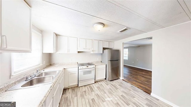 kitchen with stainless steel refrigerator, a wealth of natural light, light wood-type flooring, and electric stove