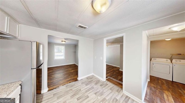 kitchen featuring light hardwood / wood-style flooring, independent washer and dryer, white cabinetry, and stainless steel refrigerator