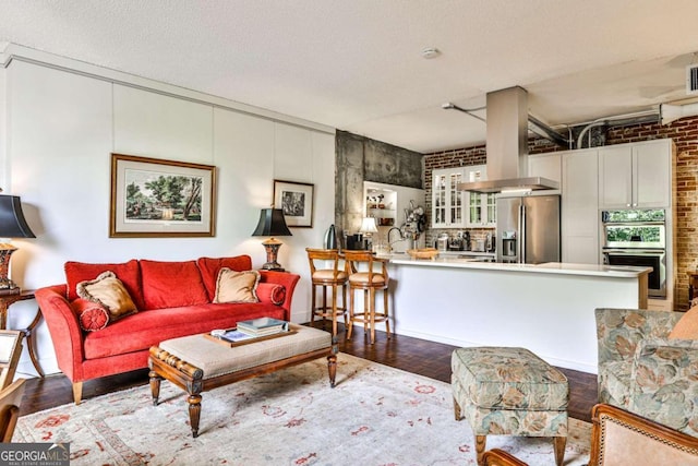 living room with brick wall, a textured ceiling, wood-type flooring, and sink