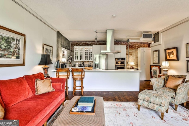 living room with brick wall, wood-type flooring, and a textured ceiling