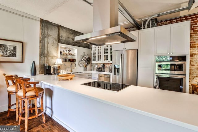 kitchen featuring island exhaust hood, dark parquet floors, kitchen peninsula, stainless steel appliances, and sink