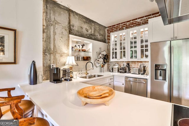 kitchen with appliances with stainless steel finishes, sink, a kitchen bar, and white cabinets