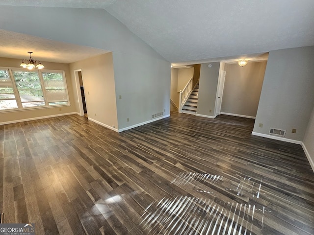 unfurnished living room with a textured ceiling, vaulted ceiling, dark hardwood / wood-style floors, and an inviting chandelier