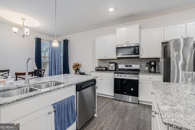 kitchen with pendant lighting, appliances with stainless steel finishes, sink, and white cabinets