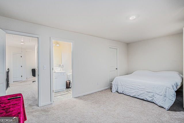 bedroom with ensuite bathroom and light colored carpet