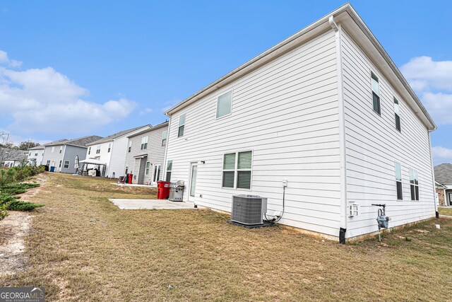 back of house featuring a lawn and central AC