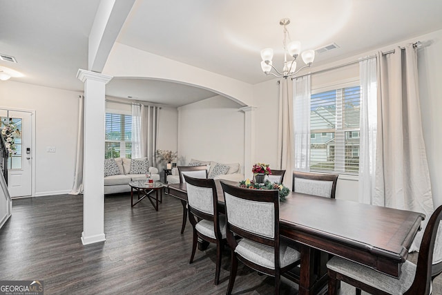 dining room with dark hardwood / wood-style flooring, decorative columns, and an inviting chandelier