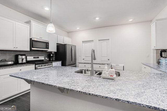 kitchen featuring white cabinets, decorative backsplash, hanging light fixtures, light stone countertops, and appliances with stainless steel finishes