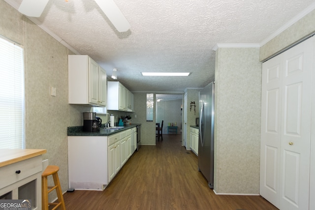 kitchen featuring white cabinetry, stainless steel refrigerator, ornamental molding, dark wood-type flooring, and sink