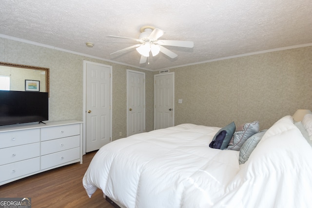 bedroom with ceiling fan, ornamental molding, a textured ceiling, and dark hardwood / wood-style floors