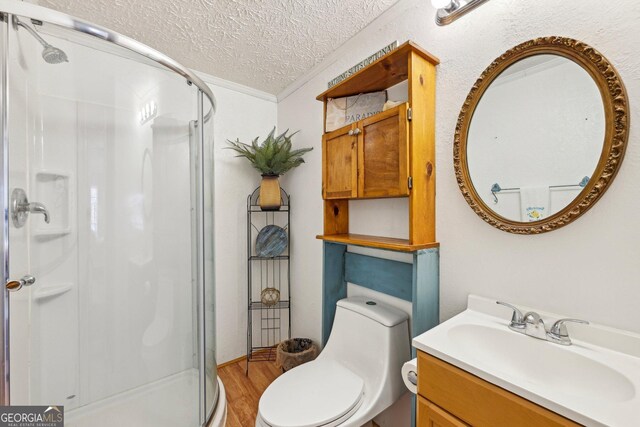 bathroom with wood-type flooring, ornamental molding, vanity, a textured ceiling, and ceiling fan