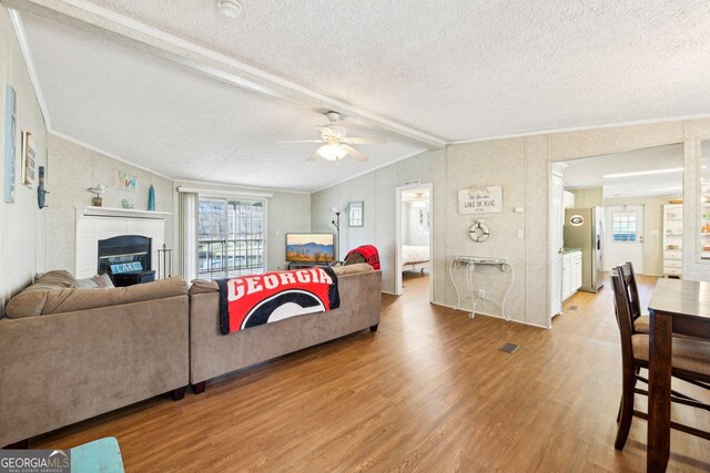 living room featuring crown molding, wood-type flooring, vaulted ceiling with beams, and ceiling fan