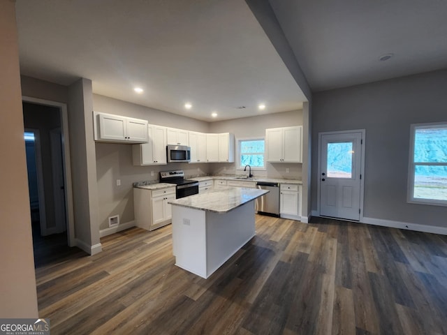 kitchen with white cabinetry, a kitchen island, light stone countertops, and appliances with stainless steel finishes