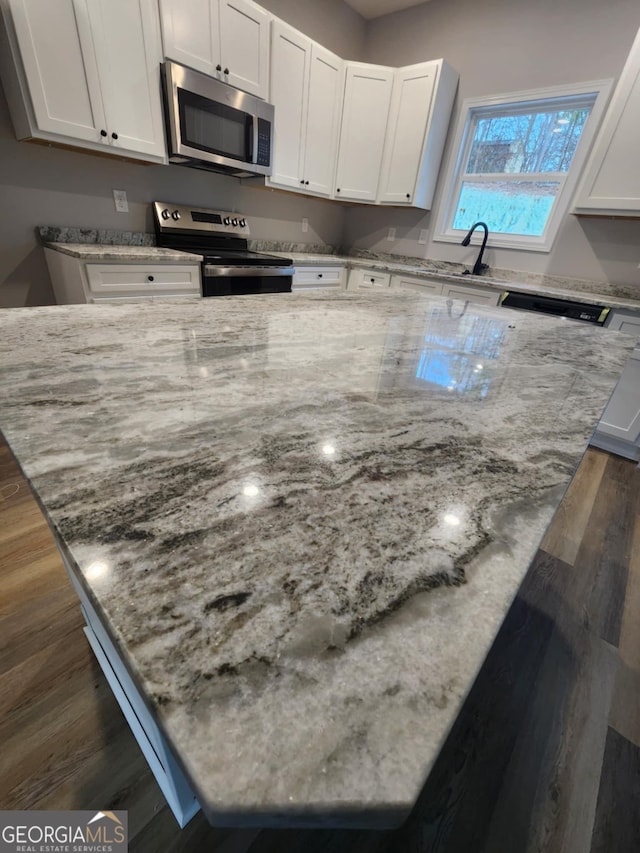 kitchen with light stone countertops, stainless steel appliances, and white cabinets