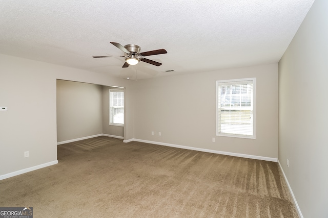 unfurnished room featuring a textured ceiling, carpet floors, a healthy amount of sunlight, and ceiling fan