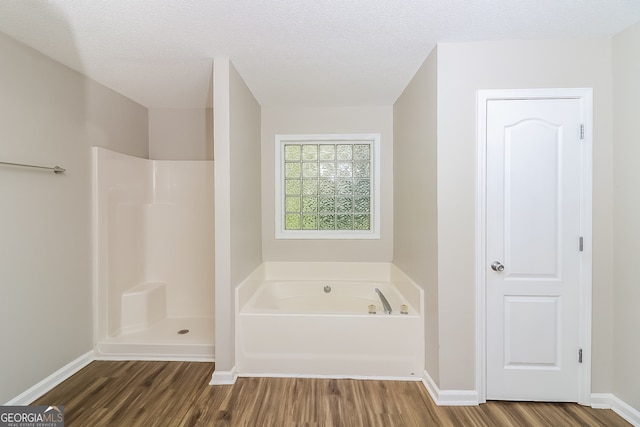 bathroom with wood-type flooring, a textured ceiling, and separate shower and tub