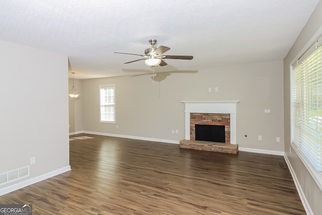 unfurnished living room with a textured ceiling, dark wood-type flooring, and ceiling fan