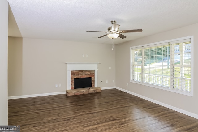 unfurnished living room featuring dark wood-type flooring, ceiling fan, a textured ceiling, and a fireplace