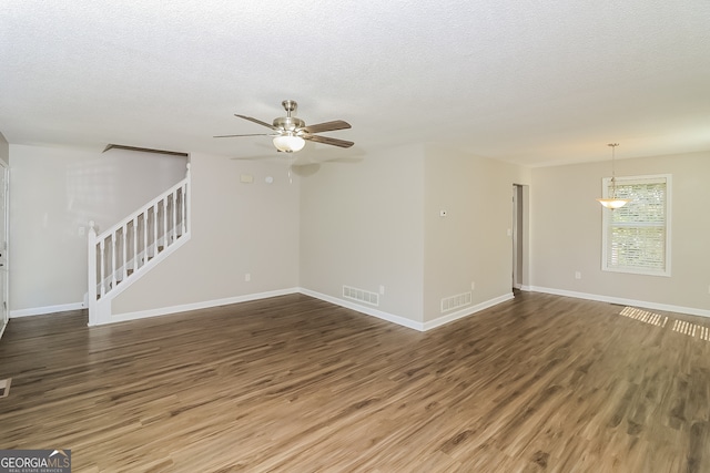 empty room featuring dark wood-type flooring, a textured ceiling, and ceiling fan