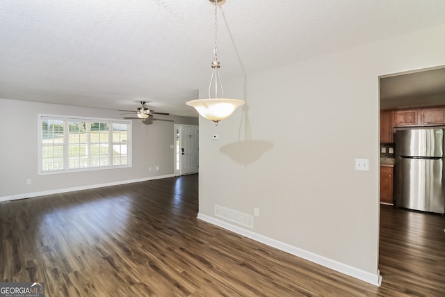 spare room featuring dark wood-type flooring, ceiling fan, and a textured ceiling