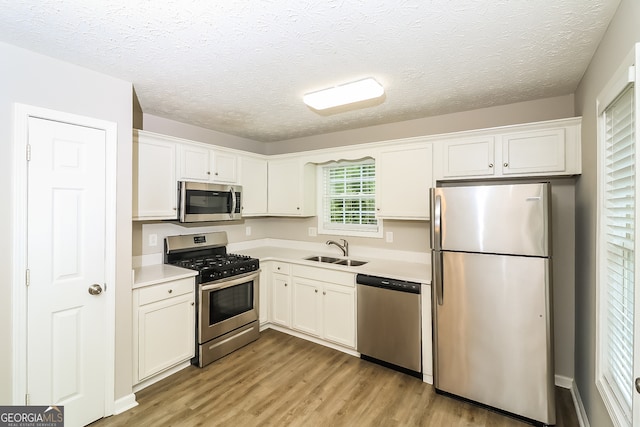 kitchen with white cabinetry, stainless steel appliances, sink, and light wood-type flooring