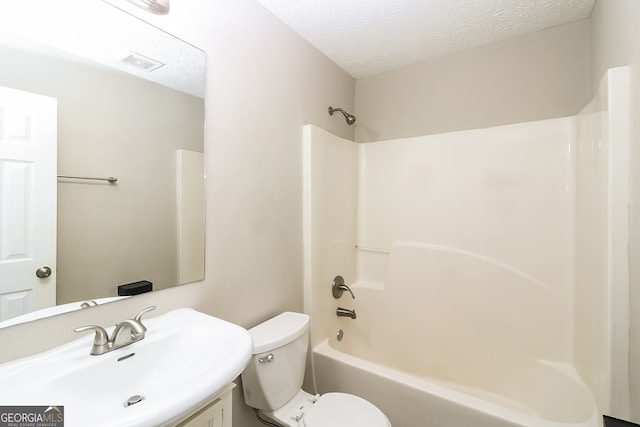 full bathroom with toilet, a textured ceiling, vanity, and washtub / shower combination