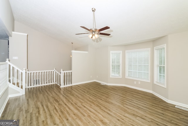 empty room with ceiling fan, a textured ceiling, vaulted ceiling, and hardwood / wood-style floors