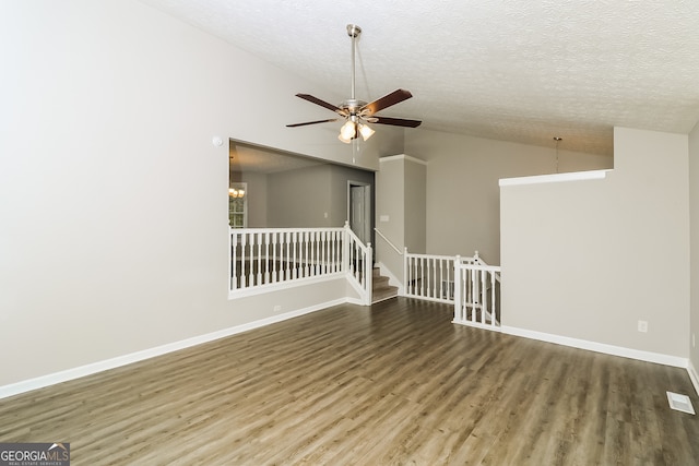 spare room with a textured ceiling, hardwood / wood-style flooring, ceiling fan with notable chandelier, and vaulted ceiling