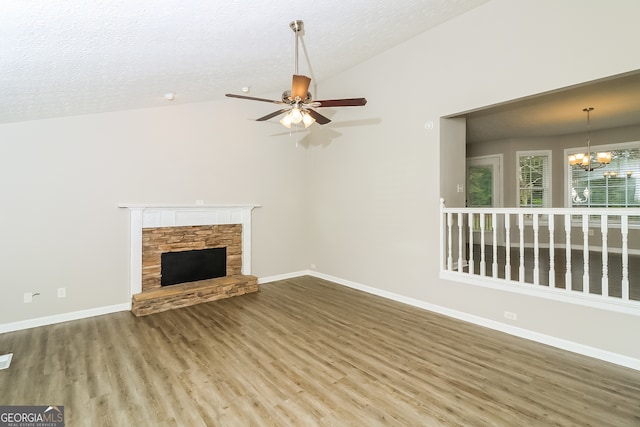 unfurnished living room with a fireplace, hardwood / wood-style flooring, vaulted ceiling, a textured ceiling, and ceiling fan with notable chandelier