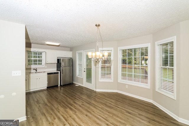 kitchen with hanging light fixtures, appliances with stainless steel finishes, white cabinetry, dark wood-type flooring, and sink