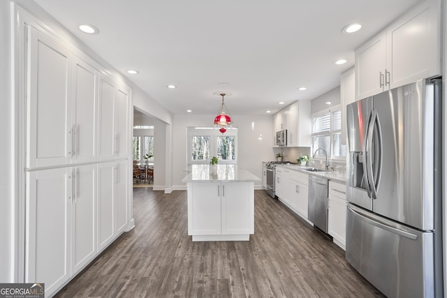 kitchen with pendant lighting, white cabinets, sink, a kitchen island, and stainless steel appliances