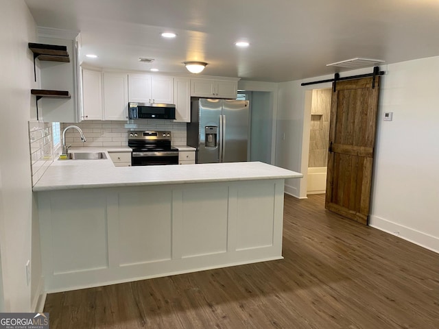 kitchen featuring sink, stainless steel appliances, a barn door, dark hardwood / wood-style flooring, and white cabinets