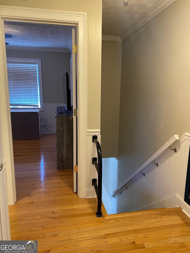 staircase with ornamental molding and hardwood / wood-style flooring