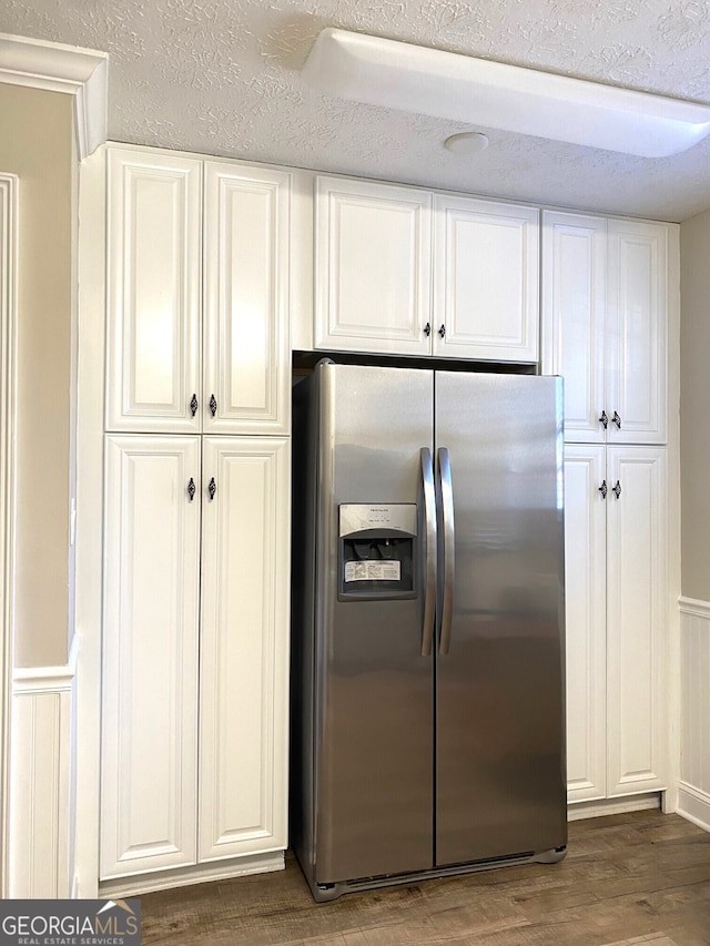 kitchen with stainless steel refrigerator with ice dispenser, a textured ceiling, dark hardwood / wood-style floors, and white cabinetry