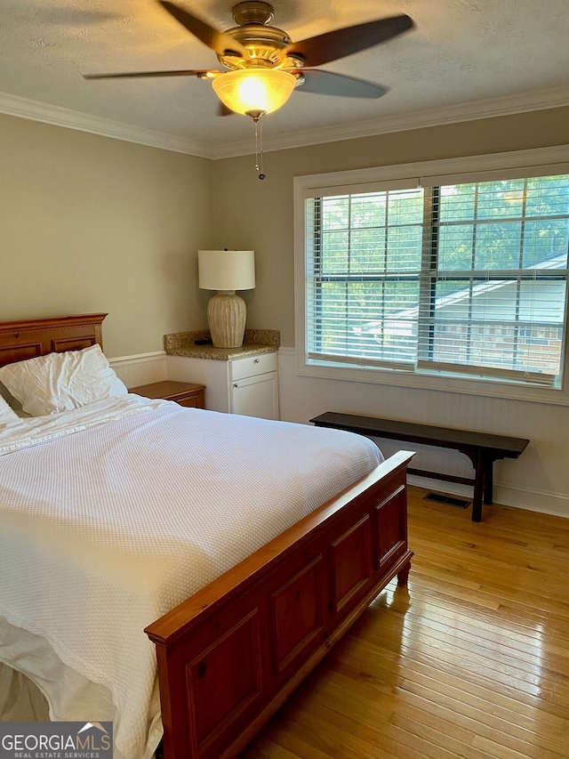 bedroom with ceiling fan, crown molding, and light hardwood / wood-style flooring