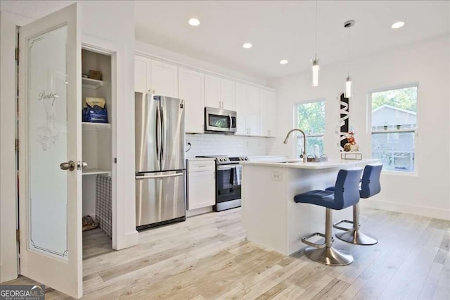 kitchen with stainless steel appliances, an island with sink, and white cabinets