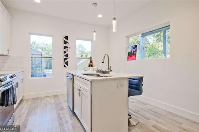 kitchen featuring white cabinets, a healthy amount of sunlight, sink, and an island with sink