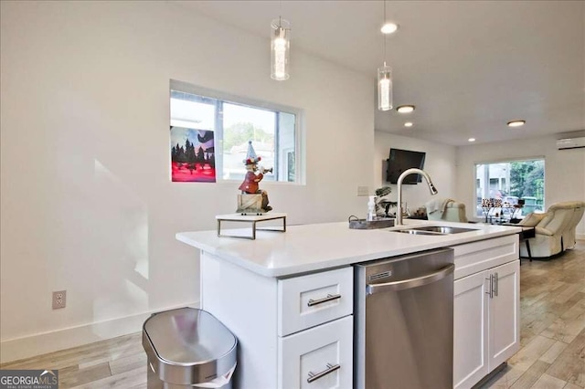 kitchen with hanging light fixtures, white cabinetry, a kitchen island with sink, stainless steel dishwasher, and light wood-type flooring