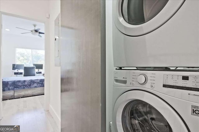 clothes washing area with stacked washer / dryer, light hardwood / wood-style floors, and ceiling fan