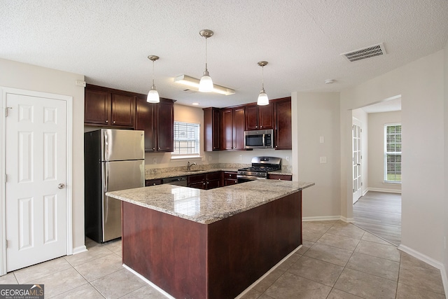 kitchen featuring sink, light stone countertops, a center island, appliances with stainless steel finishes, and a textured ceiling