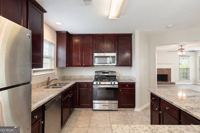 kitchen featuring stainless steel appliances, sink, a fireplace, and a wealth of natural light